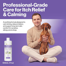 A man in a beige sweater and white pants sits cross-legged on a purple background, holding a small brown dachshund. Large white text at the top reads 'Professional-Grade Care for Itch Relief & Calming.
