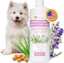 A bottle of Aromapet Sensitive Skin & Gentle Care Wash Gentle Shampoo shown with a white fluffy puppy, purple and white flowers, green aloe leaves, and bath beads on a white background.